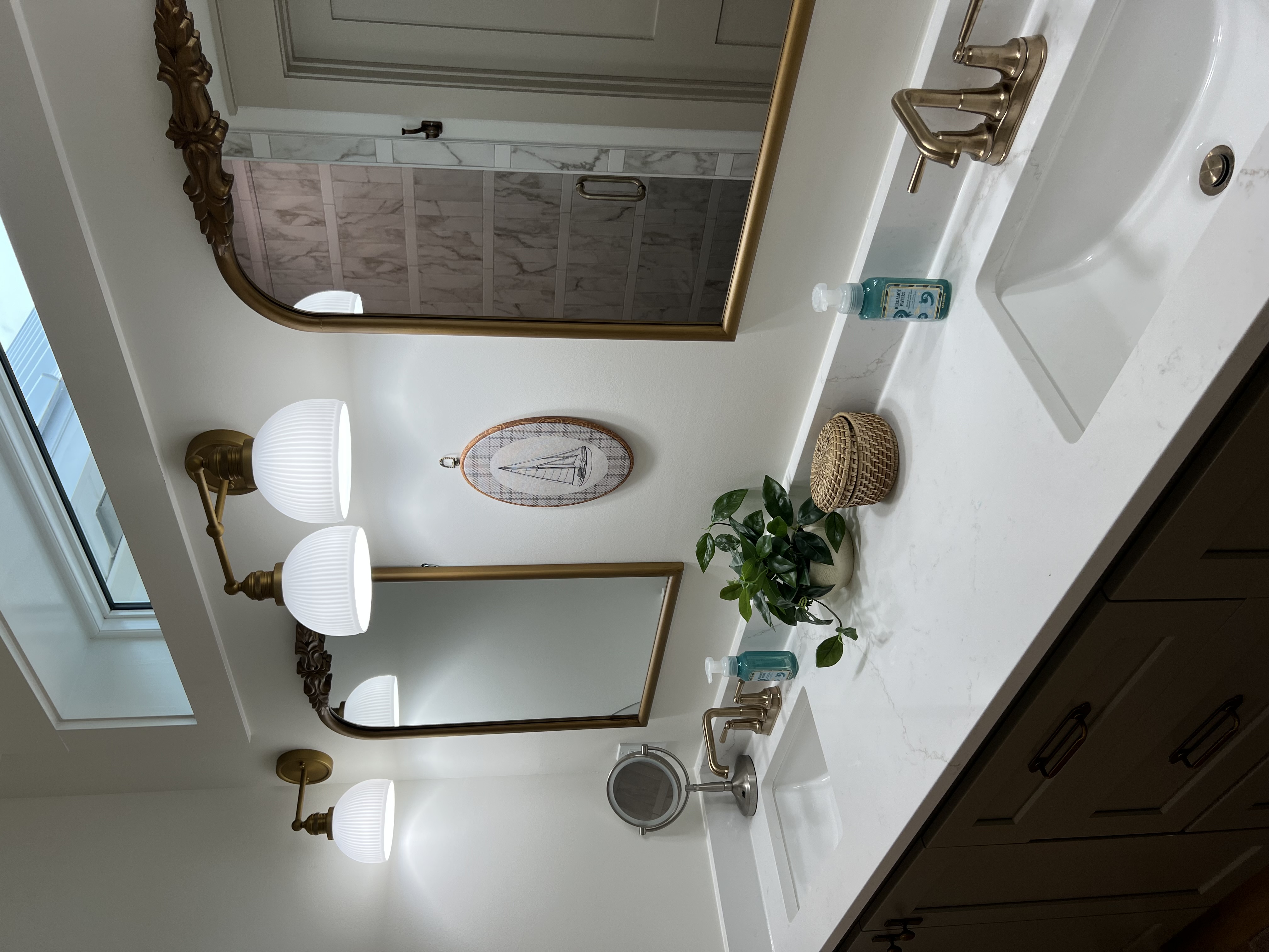Master bathroom vanity with gold fixtures and ornate mirror